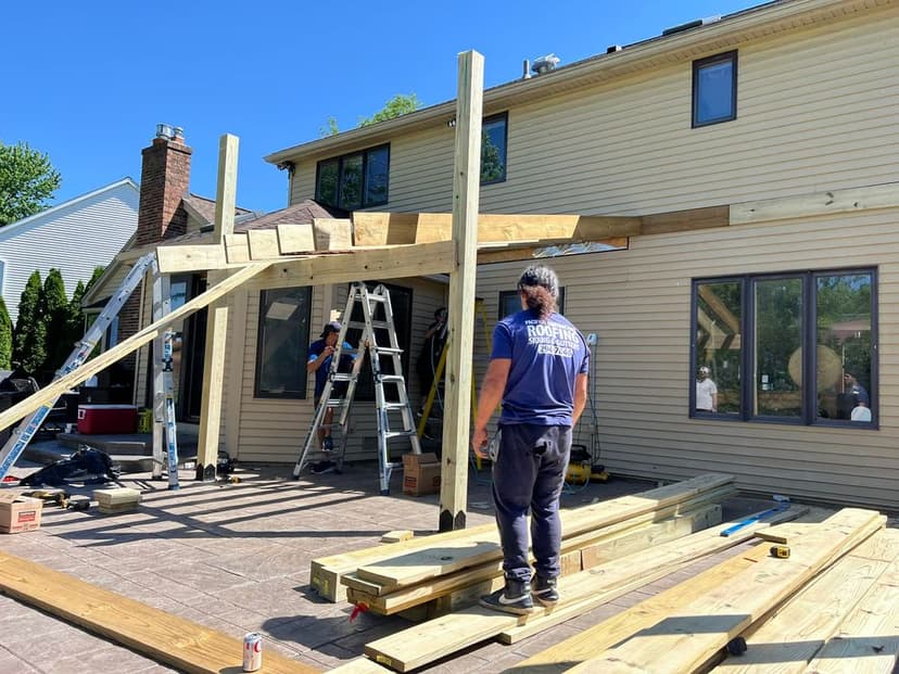 Home improvement project: workers building a wooden patio structure with ladders and materials.
